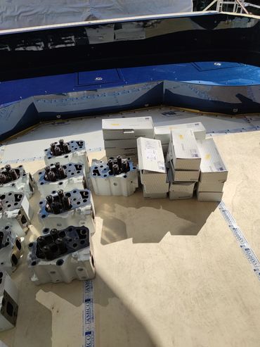 Engine parts and boxes on a surface with blue panel background.