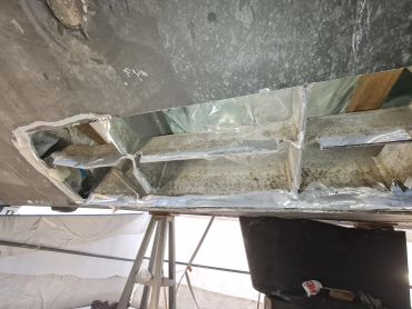 Damaged metallic sheet with plastic coverings in a workshop.