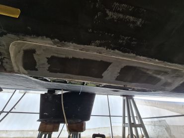 Boat hull being repaired or cleaned in a dry dock.
