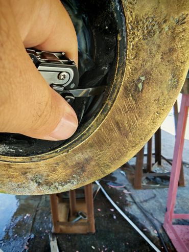 Fingers using a multitool inside a metal object.