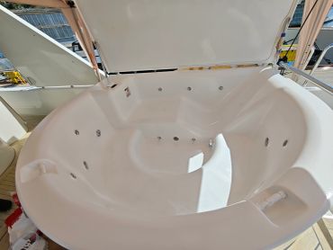 Empty white jacuzzi tub with built-in jets and headrests.
