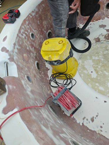 Worker refurbishing a fiberglass pool or spa.