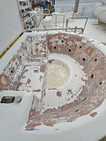 A worn-out, stripped jacuzzi on a boat deck needing restoration.