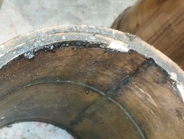 Close-up of a cracked, rusted metal pipe with white residue on its edges.