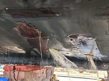 Water leaking through holes in a ceiling with visible damage.