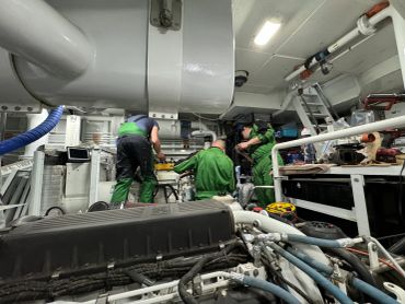 Technicians working on machinery in an industrial engine room.