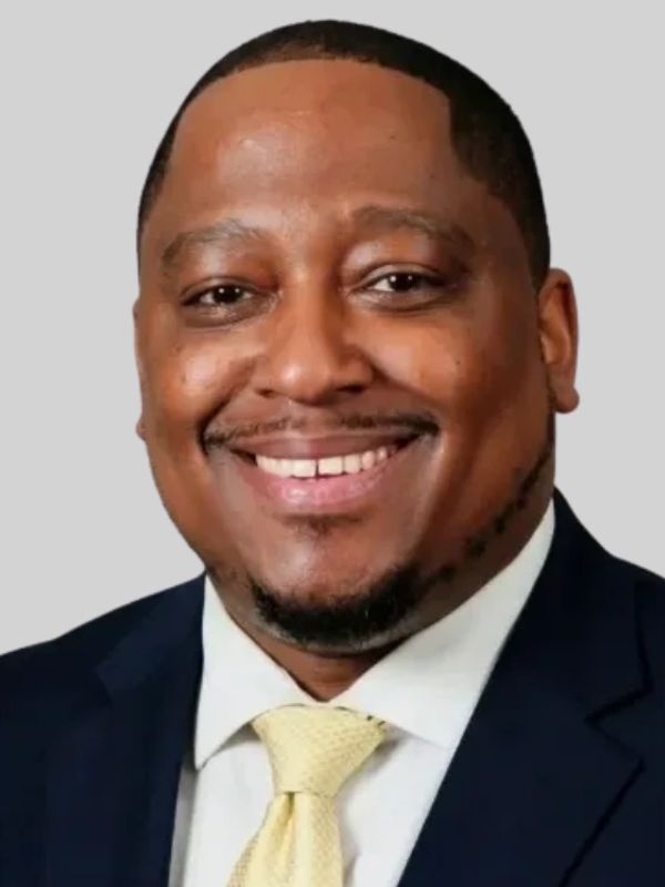Smiling man in a suit with a yellow tie.