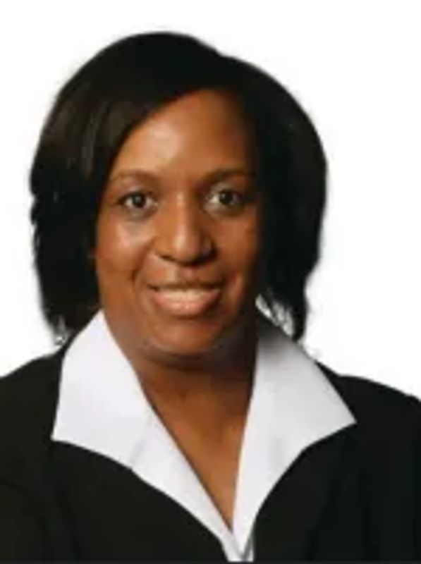 Professional portrait of a smiling woman wearing a black blazer and white shirt.