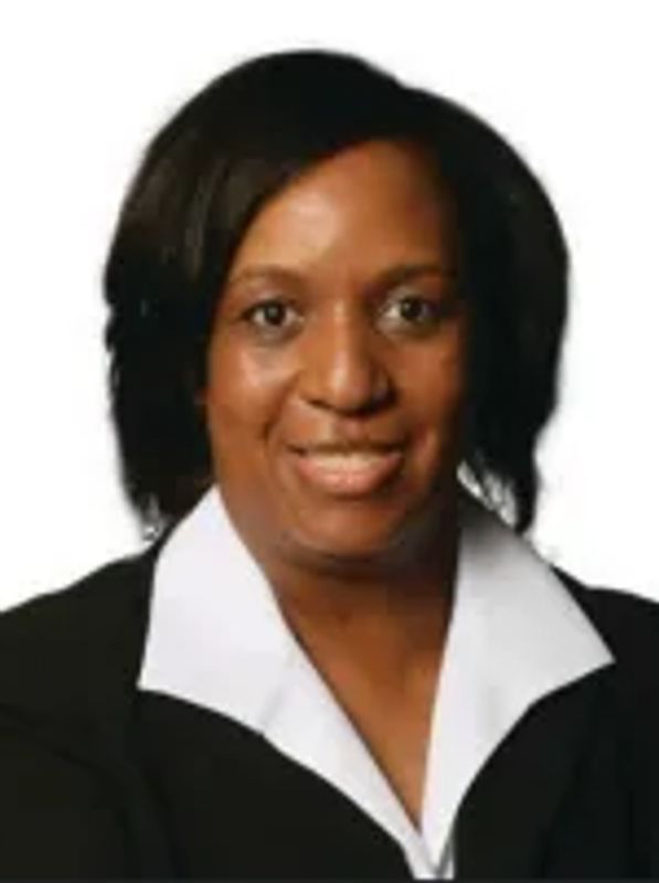 Professional portrait of a smiling woman wearing a black blazer and white shirt.
