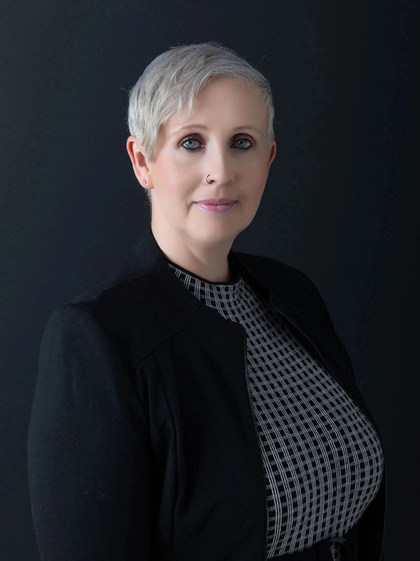 Professional woman with short gray hair and blue eyes in a black jacket.