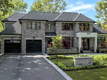 Modern two-story house with stone facade and black garage doors.