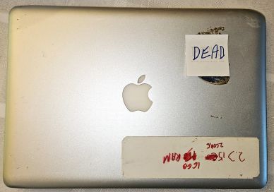 Old Apple laptop with 'DEAD' note on its lid.