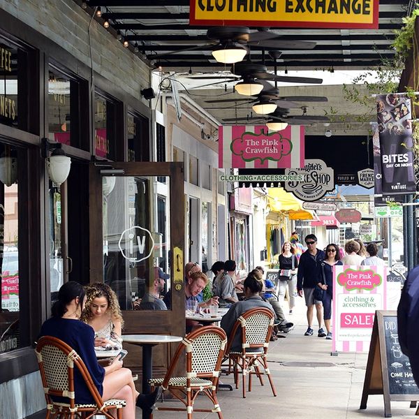 Outdoor café seating and people walking in a shopping area.