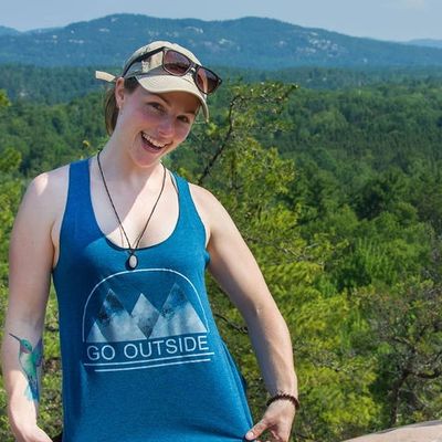 Meagan is showing off a blue tank top that says go outside, while on her women's yoga retreat