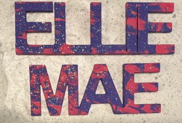 The name Ellie Mae painted purple and pink with purple and pink glitter