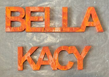 The names Bella and Kacy painted in several shades of orange