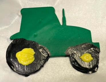 Large green tractor with black tires and yellow wheels