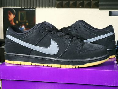 Black Nike sneakers with gray swoosh on purple box.