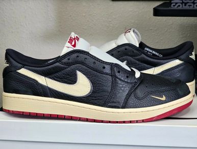 Black and cream Nike sneakers with red soles on a white surface.
