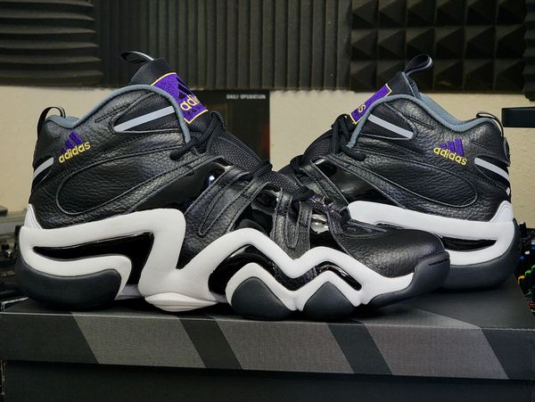 Black and white Adidas basketball shoes with purple accents.
