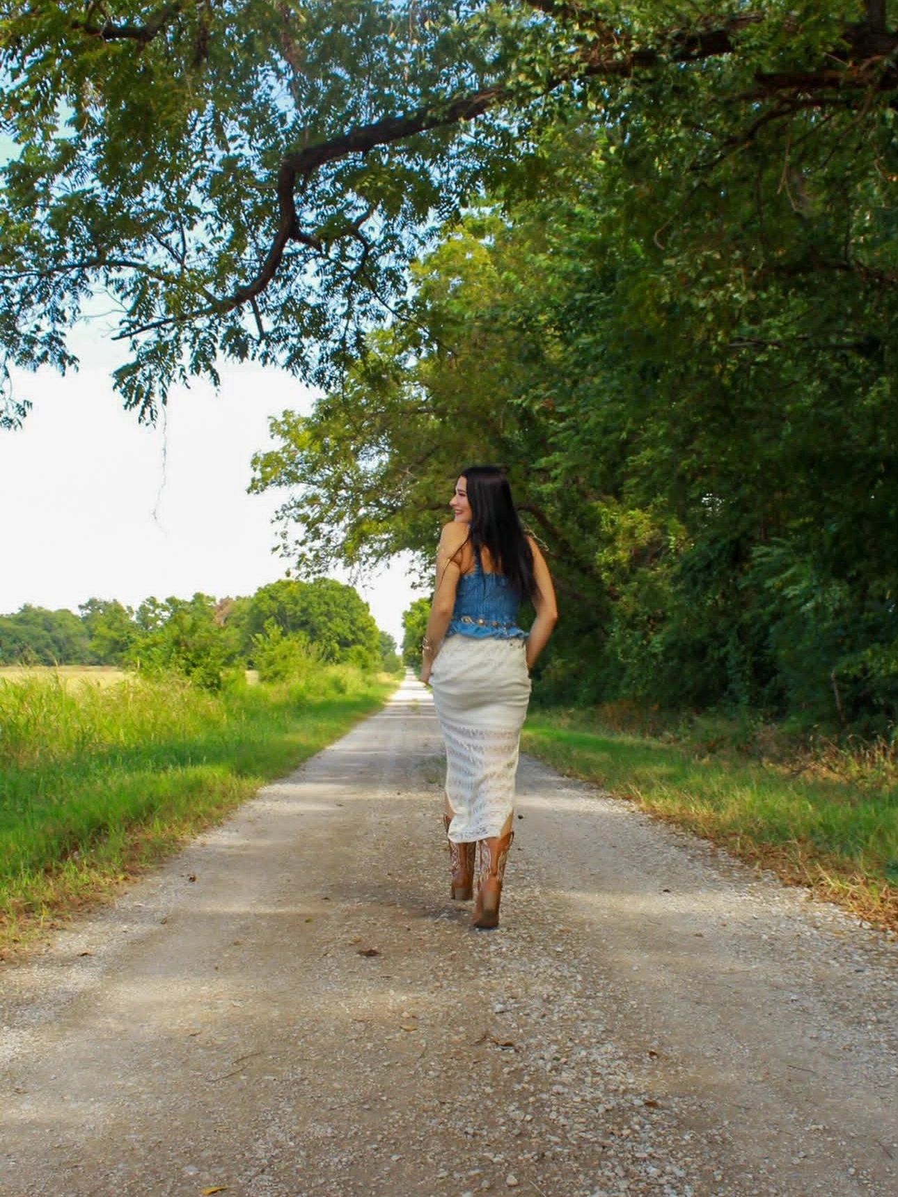 Woman walking on a tree-lined dirt road.