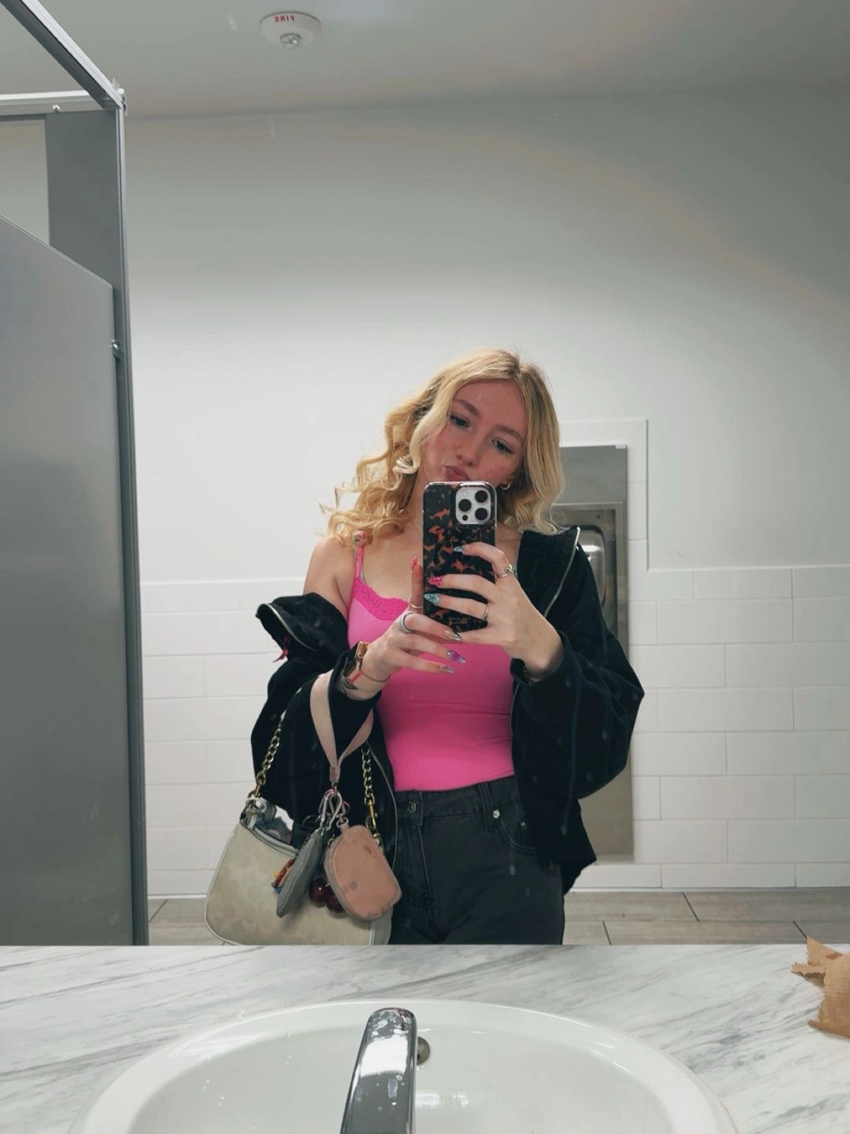 Young woman taking a mirror selfie in a bathroom.