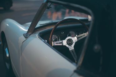 Classic white convertible car with wooden steering wheel.