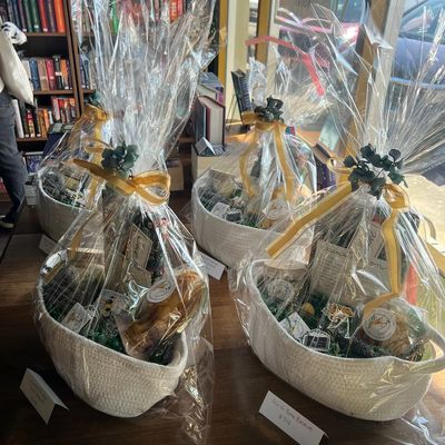 Gift baskets wrapped in clear plastic with gold ribbons on a table.