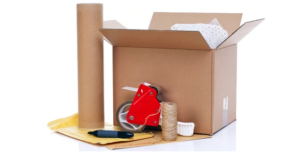 a cardboard box, packing tape, a roll of paper, twine, and a marker sitting on a white table