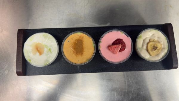 Four dessert cups with varied toppings on a black tray.