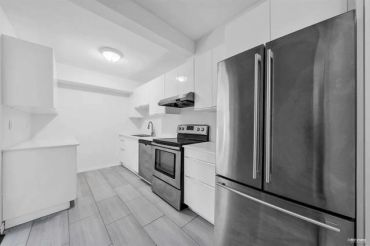 Modern kitchen with stainless steel appliances and white cabinetry.