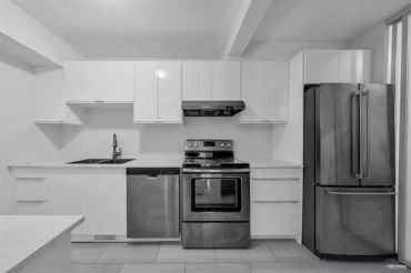 Modern kitchen with stainless steel appliances and white cabinetry.