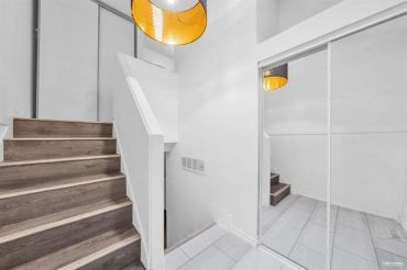 Modern staircase with wooden steps and mirrored closet doors.
