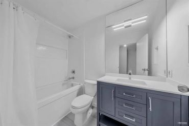 Modern bathroom with white walls and a dark vanity cabinet.