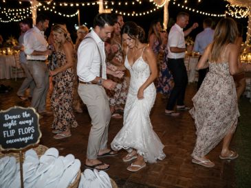 Couple dancing happily at a festive wedding reception with string lights.