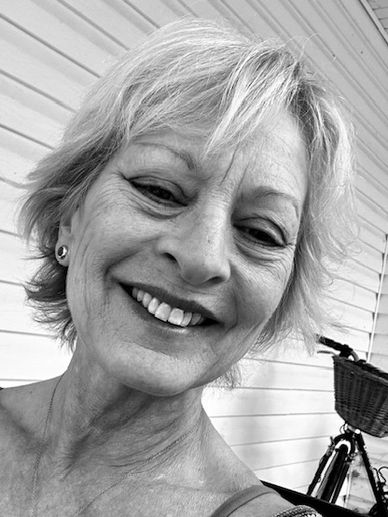 Smiling older woman taking a close-up selfie in black and white.