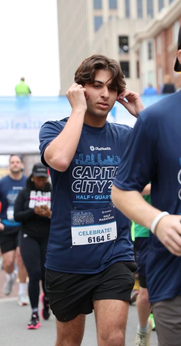Runner adjusting earphones during Capital City Half Marathon event.