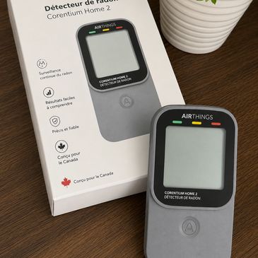 Détecteur de radon Corentium Home 2 sur une table en bois.