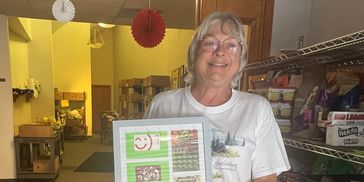 Smiling woman holding a tray of desserts in a kitchen.