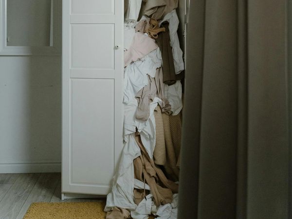 Closet with clothes hanging out of it 
