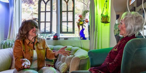 Two women engaged in a lively conversation on sofas in a cozy room.