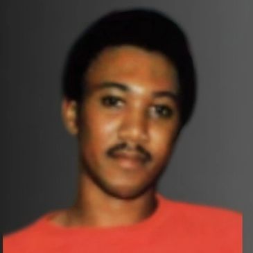 Portrait of a young man with a mustache wearing a red shirt.