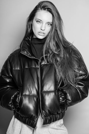 Black and white portrait of a woman in a leather puffer jacket.