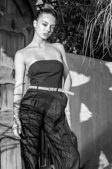 Young woman in strapless outfit posing outdoors with shadows playing on her.