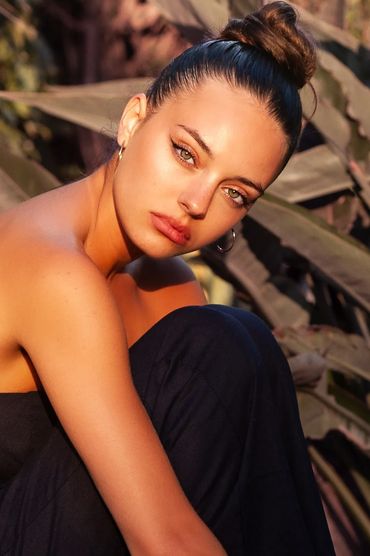 Woman with a high bun and hoop earrings in natural light.