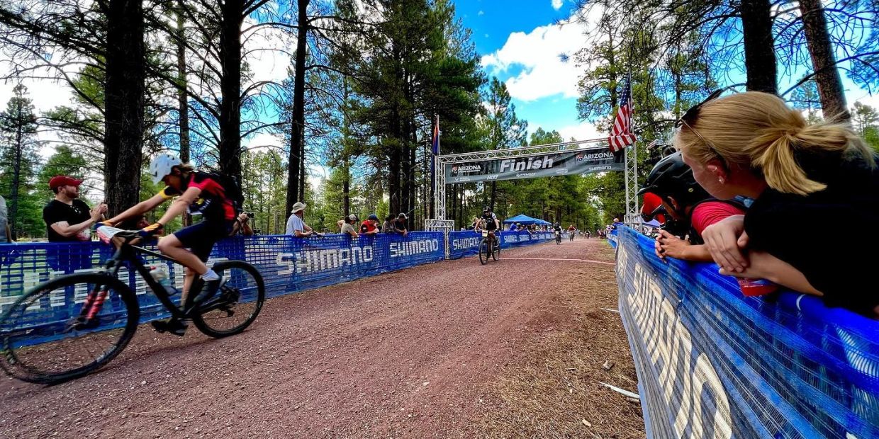 FINSIH LINE OF A MOUNTAIN BIKE RACE WITH A "YOUTH ON TRACK" ATHLETE CROSSING OVER.