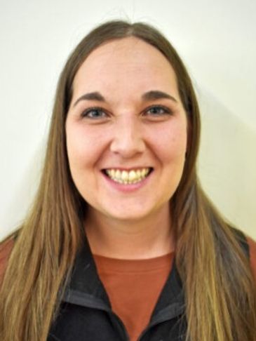 Smiling woman with long brown hair and casual attire.