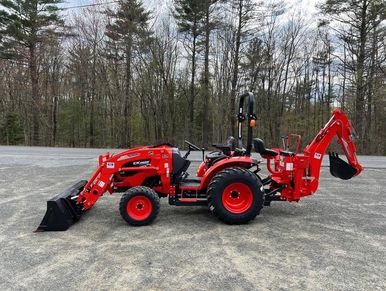 Red compact tractor with front loader and backhoe attachment on gravel.