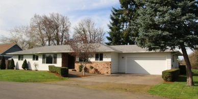 Single-story suburban house with a two-car garage and well-maintained lawn.
