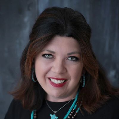 Smiling woman with turquoise jewelry and dark hair.